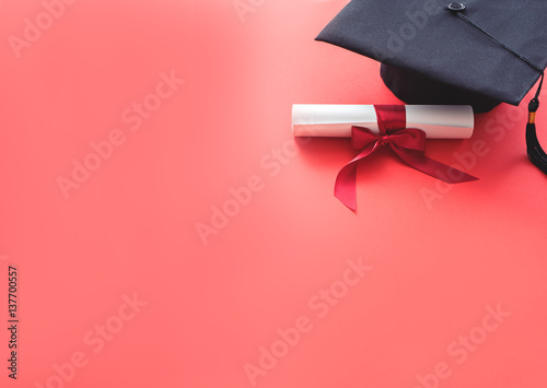 academic hat with diploma on red background