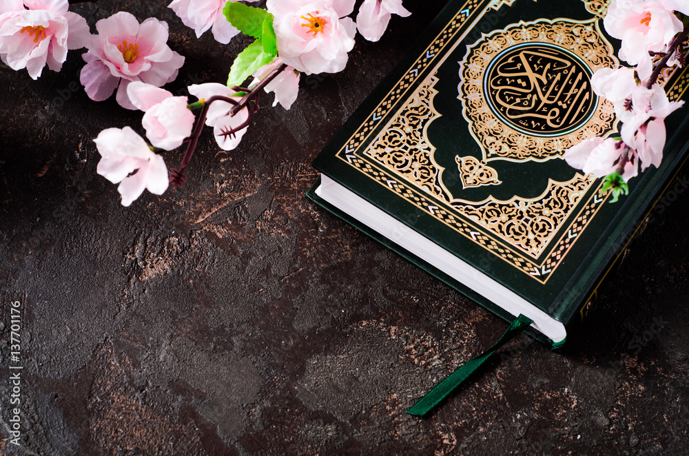 Islamic Book Koran and spring flowers brunch on dark background with