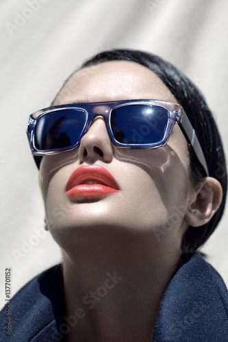 Fashion outdoor portrait of a young beautiful brunette girl in sunglasses with stylish hairstyle.