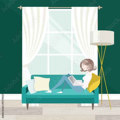 Female freelancer working on her laptop, sitting on the sofa