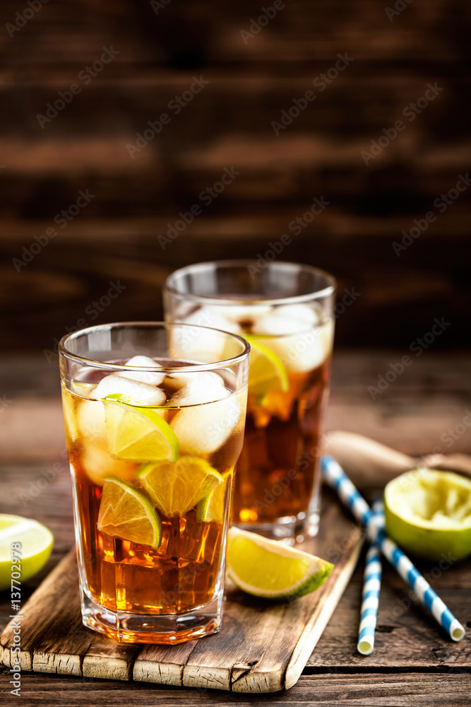 Cuba Libre or long island iced tea cocktail with strong drinks, cola, lime and ice in glass, cold longdrink Cuba Libre or long island iced tea cocktail with strong drinks, cola, lime and ice in glass, cold longdrink