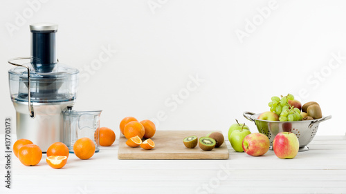 Modern electric juicer and various fruit on kitchen counter, healthy lifestyle concept