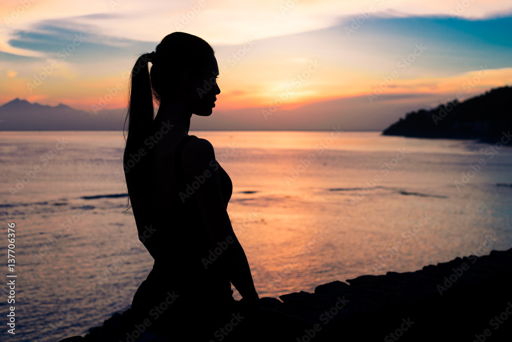 Silhouette of a woman sitting near the ocean