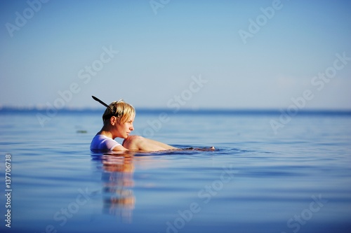Young woman in white shirt lie on back and relaxing in blue sea water fashion shot