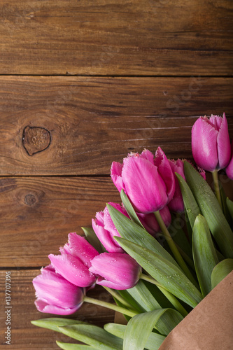 Fototapeta Naklejka Na Ścianę i Meble -  Pink tulips in a package of craft on the wooden background. Pink tulip. Tulips. Flowers. Flower background. Flowers photo concept. Holidays photo concept. Copyspace