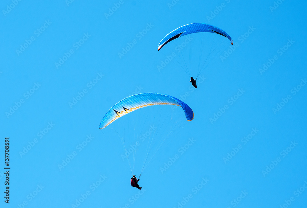Two paragliders flying in the blue sky. Paragliding. Two paragliders flying in the blue sky. Paragliding.