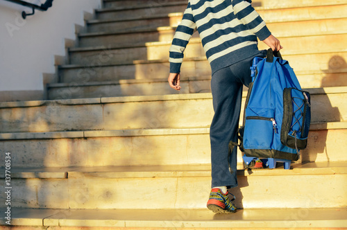 Back view of boy walking on stairs outdoors building background photo