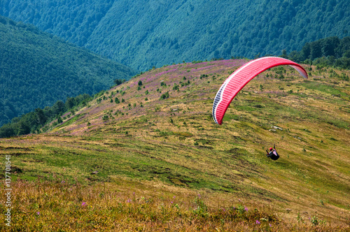 Paragliding in the sky. Paraglider fly over the tops of the mountains in summer sunny day. Carpathians, Ukraine.