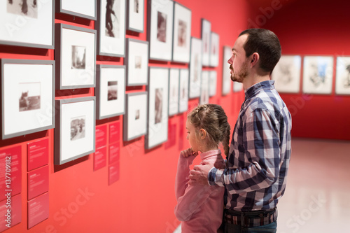 Father and girl exploring exhibition of photos photo