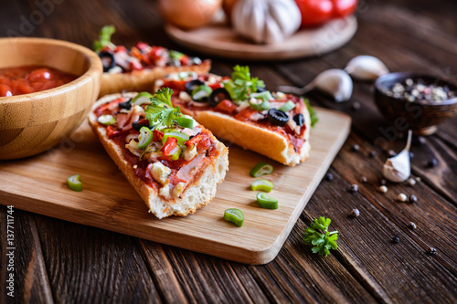 Baguette pizza with bacon, salami, cheese and vegetable