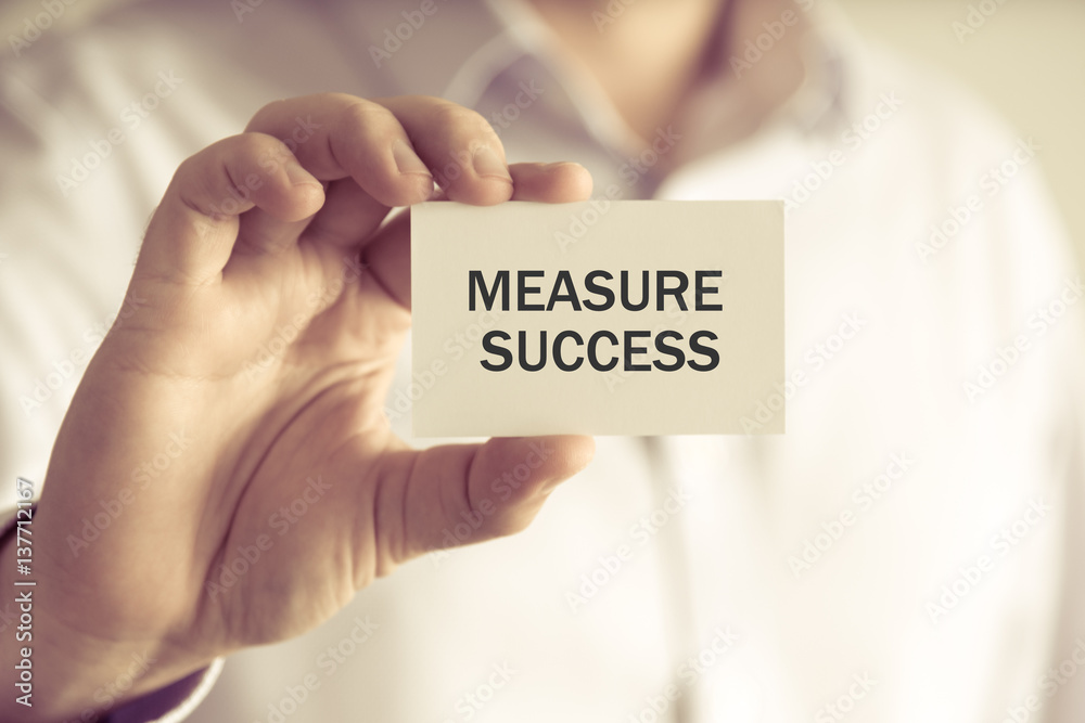 Businessman holding MEASURE SUCCESS message card Businessman holding MEASURE SUCCESS message card