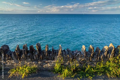 Coast in north Devon. Near the town of Ilfracombe. Jagged fence in the foreground. Calm sea. Evening. UK