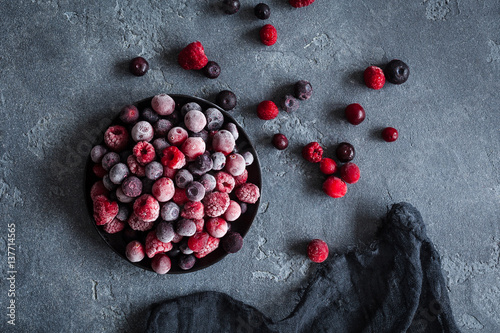 Frozen raspberry, blueberry, cranberry on dark background. Frozen fruit. Top view, flat lay