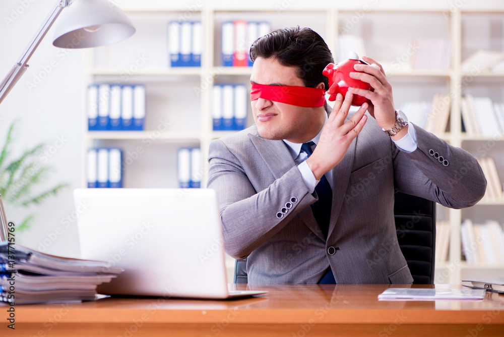 Blindfold businessman sitting at desk in office Blindfold businessman sitting at desk in office