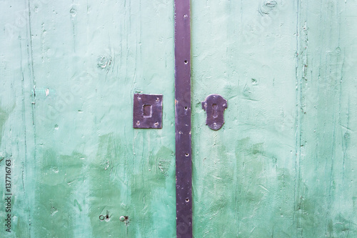 Green wooden door close up detail with rusty lock
