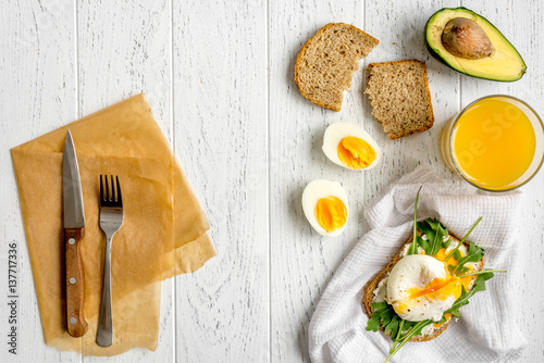 sandwich with poached eggs on wooden background top view