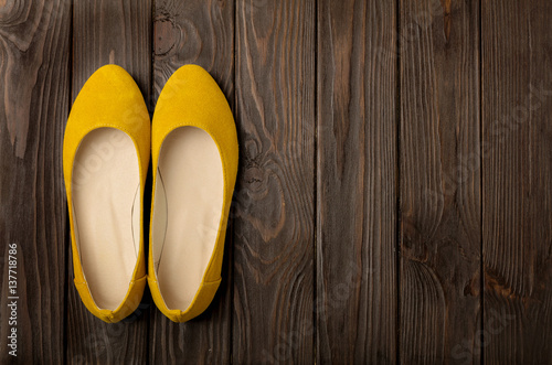 Yellow women's shoes (ballerinas) on wooden background.