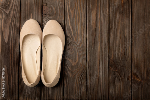 Beige women's shoes (ballerinas) on wooden background.