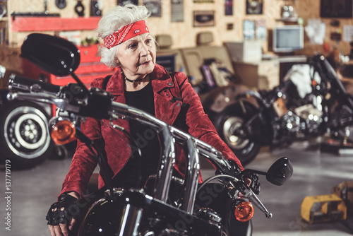 Pensive retiree locating on bike in mechanic shop