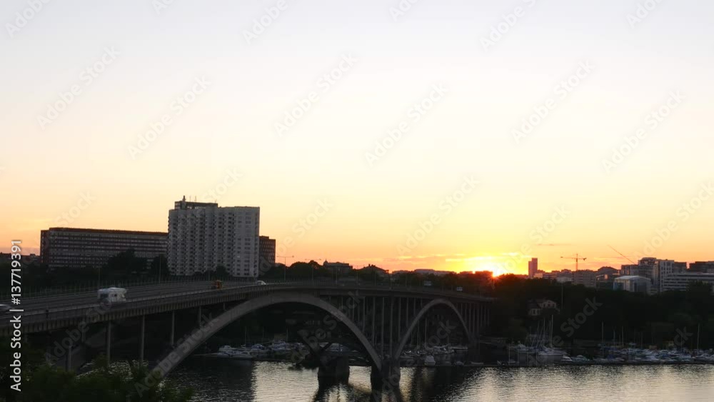 Arch bridge and river at sunset. Traffic passing by, office building in the background Arch bridge and river at sunset. Traffic passing by, office building in the background