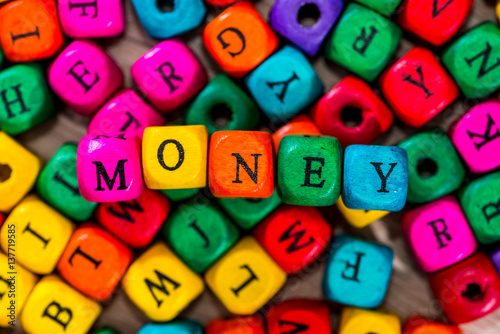 Word "money" of the colored wooden cubes on wooden desk.