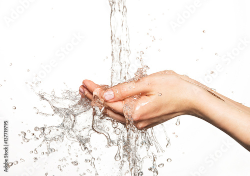 Closeup female hands under the stream of splashing water