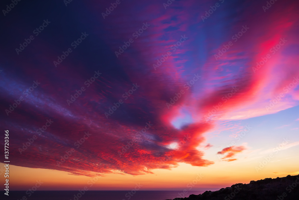 Beautiful sunset and clouds on sea. Sunset on ocean. Red and blue colors