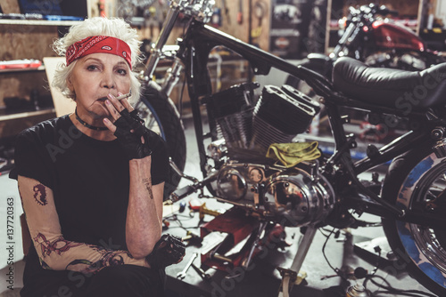 Thoughtful old woman smoking next to bike