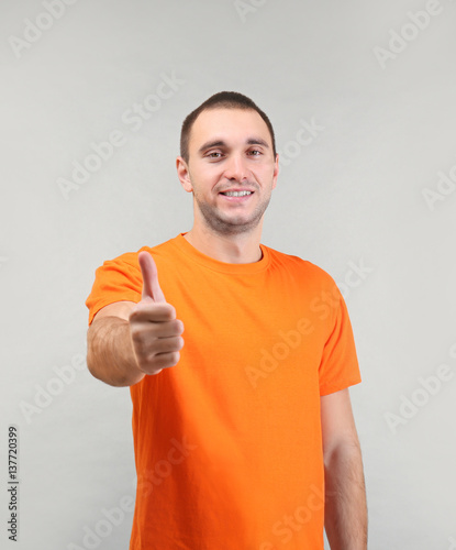 Cheerful man showing thumb up sign on light background