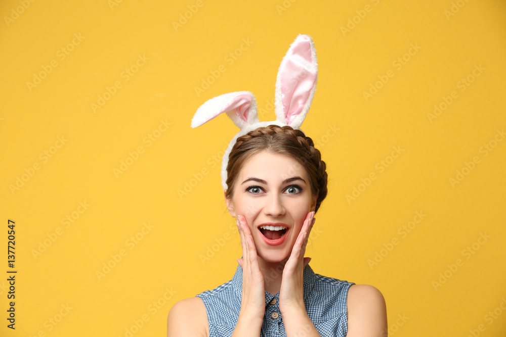 Beautiful young woman with bunny ears on color background