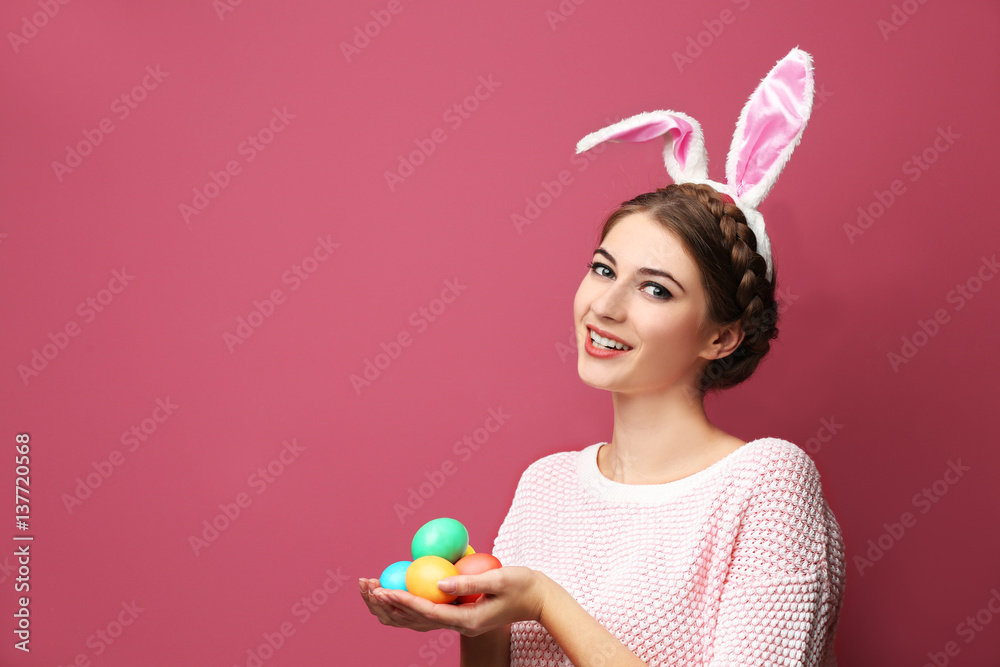 Beautiful young woman with bunny ears and Easter eggs on color background Beautiful young woman with bunny ears and Easter eggs on color background