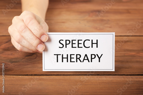 Speech therapy concept. Hand holding card on wooden background