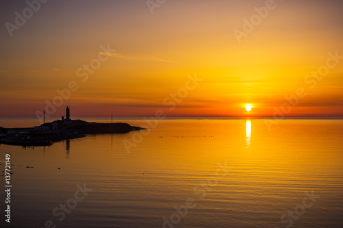 Colored sunset and ocean. Cloudy sky, sea and lighthouse