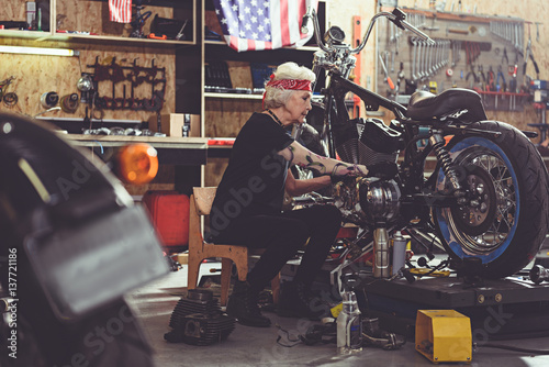 Serene grandmother repairing bike in mechanic shop