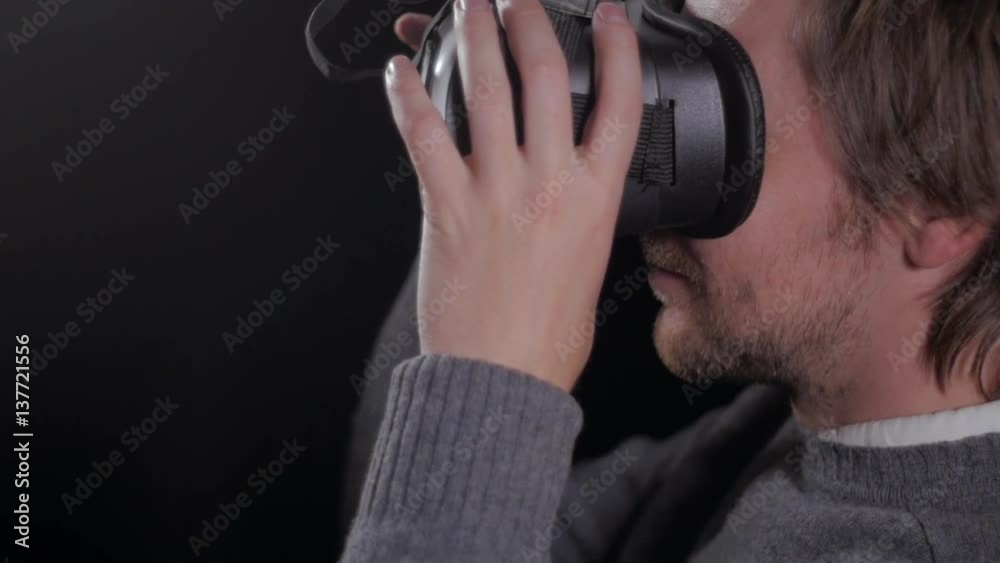 Close up of man in vr glasses playing games and reaction on black background Close up of man in vr glasses playing games and reaction on black background