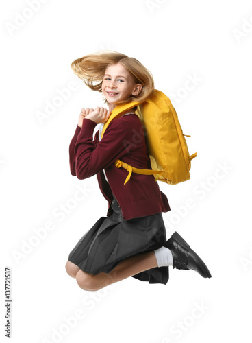 Cute girl in school uniform jumping on white background