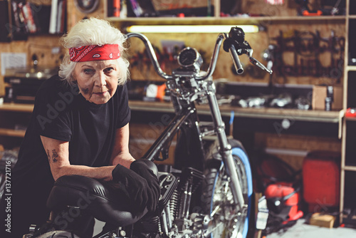 Calm tired pensioner standing near bike in garage
