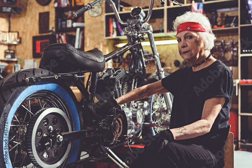 Serious retiree repairing bike in mechanic shop