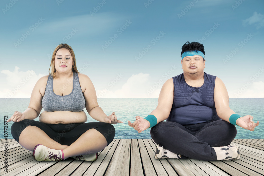 Overweight people meditating on the jetty