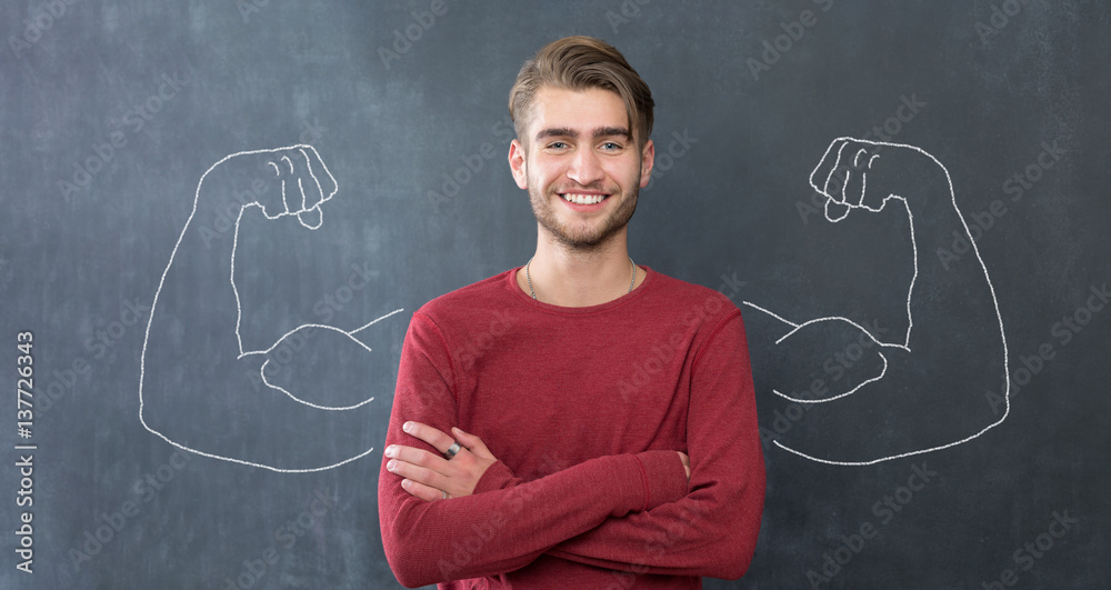 Young man against the background of depicted muscles on chalkboard