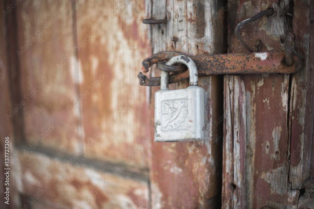 The old door locked with a padlock hanging brackets. At an angle, soft focus The old door locked with a padlock hanging brackets. At an angle, soft focus