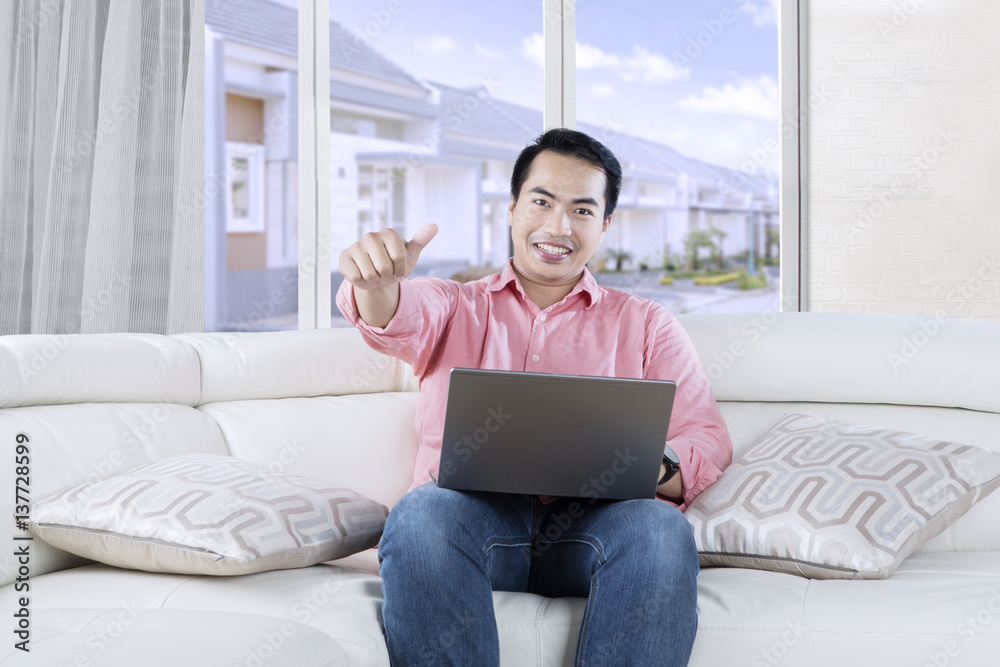 Fototapeta premium Young Asian person with laptop on couch