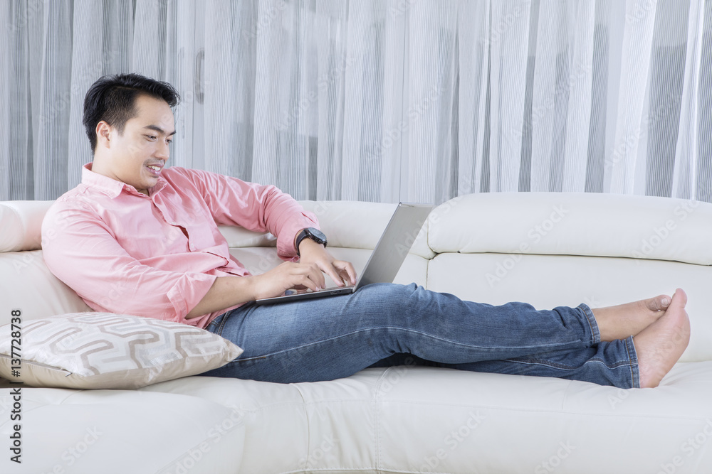 Young male relaxing on couch with laptop