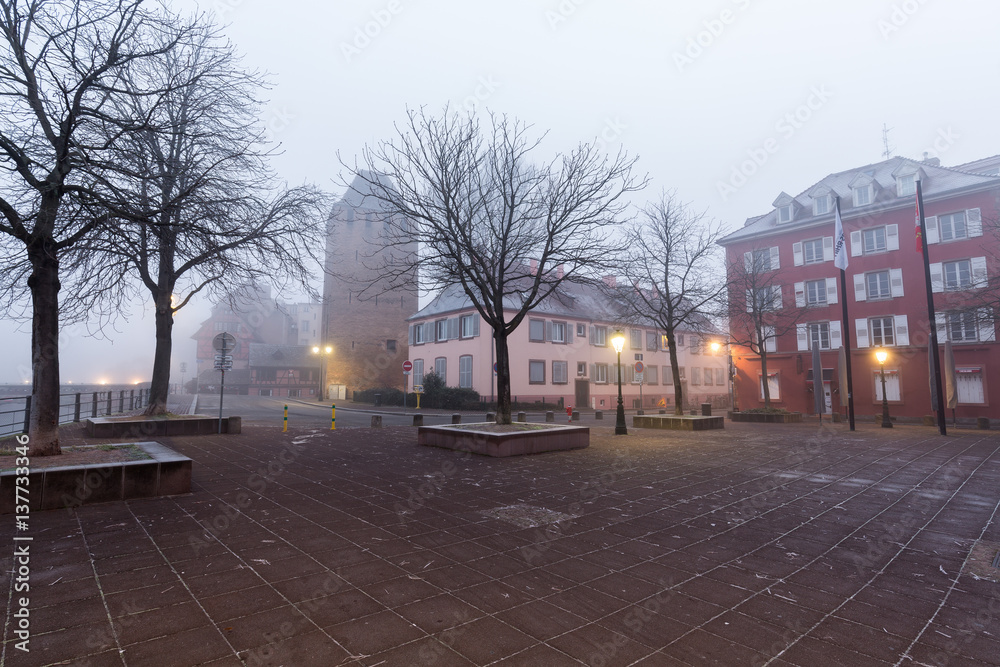 A plaza in the Petite France district of Strasbourg, France on a foggy winter morning at dawn.