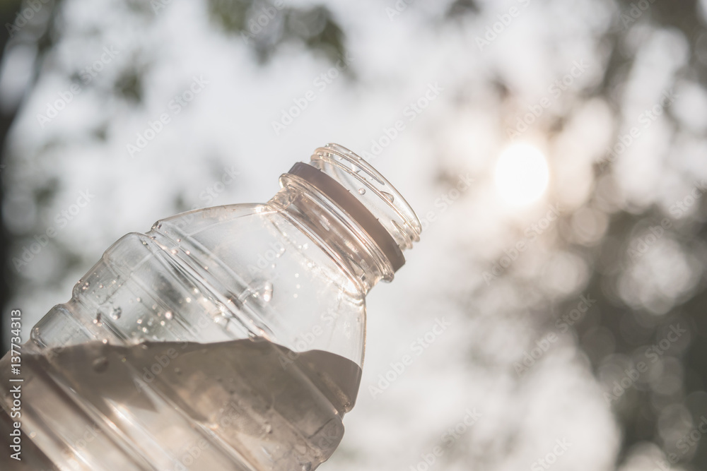 Hand holding a bottle of clean water visor sunlight in the park. Hand holding a bottle of clean water visor sunlight in the park.