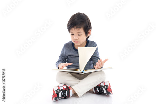 Cute asian boy reading a book on white background isolated