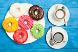 Colorful donuts and two cups of coffee on blue table
