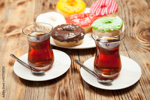 Colorful donuts and two cups of tea on a wooden table