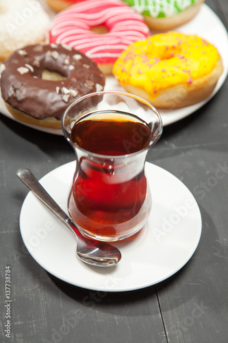Colorful donuts and cup of tea on a black table