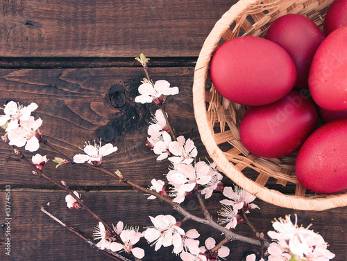 Basket with easter red eggs on rustic wooden table. Holiday background. Top view.